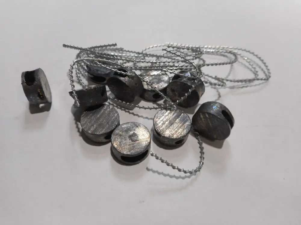 Remeha Zubehör, bestehend aus mehreren Metallteilen mit Durchgangsbohrungen und einer Schnur, zur Befestigung und Sicherung von Beuteln oder ähnlichem Material.